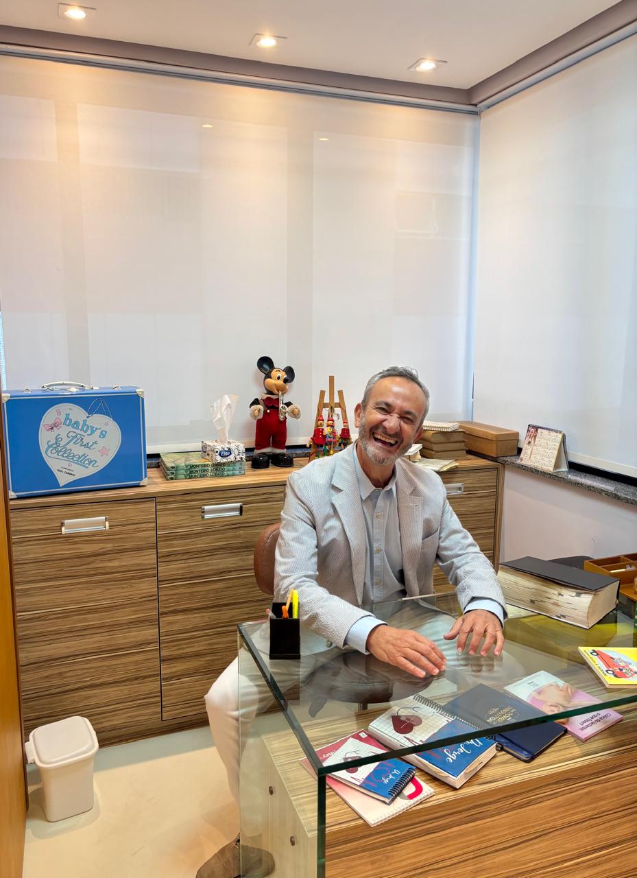 Dr. Jorge Kfouri, pediatra especialista em homeopatia infantil, sorrindo em seu consultório médico